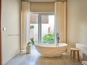 a bathroom with a large tub in front of a window at Luna Ola Villa Berawa in Canggu +42 photos
