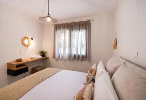 a bedroom with a bed and a desk and a window at Vardas Luxury Houses in Lefkada