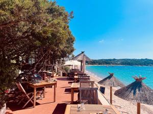 a restaurant on the beach with tables and umbrellas at Résidence Domaine De Caranella in Porto-Vecchio