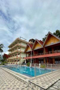 a building with a swimming pool in front of it at Mas Cottages in Tuk Tuk