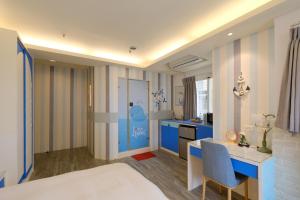 a bedroom with blue and white walls and a desk and a kitchen at 85 Asia Hotel in Kaohsiung