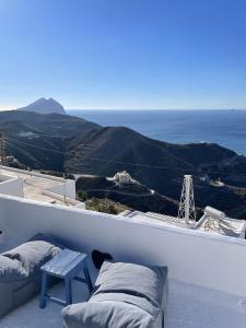 a balcony with two beds and a bench and the ocean at Anafi Tholos House in Anafi