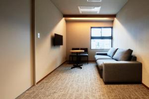 a living room with a couch and a table at &HOTEL HAKATA in Fukuoka