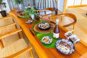 Inbu沖縄の空 海 森を贅沢に独り占めできる森の中の隠れ家的一张木桌上摆着几盘食物和一瓶酒