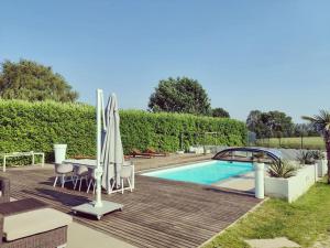a backyard with a swimming pool and a wooden deck at Guest house with private pool & jacuzzi in Velddriel