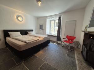 a bedroom with a bed and a red chair at Casa Grillino in Locarno