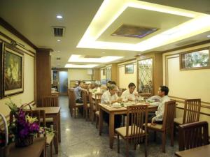 a group of people sitting at tables in a restaurant at Lenid De Ho Guom Hotel in Hanoi