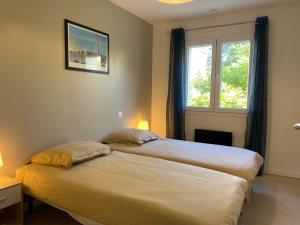 Un dormitorio con dos camas y una ventana. en Villa Perle du Rouergue, en Villefranche-de-Rouergue