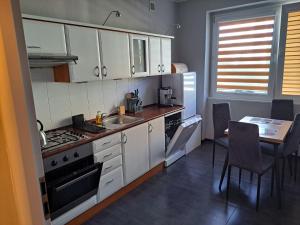 kuchnia z białymi szafkami i stołem z krzesłami w obiekcie Comfortable Apartment close to Spodek w mieście Katowice