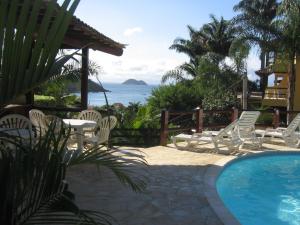 - une piscine avec des chaises et une table et l'océan dans l'établissement BUZIOS CASA POR doSOL noMAR PRAIA ePISCINA, à Búzios