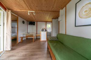 a living room with a green couch and a table at Camping Le Mont Libre - Cottage & espace nature - Gannat in Gannat