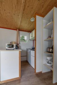 a kitchen with white appliances and a wooden ceiling at Camping Le Mont Libre - Cottage & espace nature - Gannat in Gannat