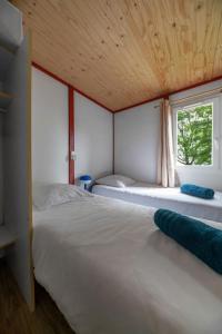 two beds in a room with a window at Camping Le Mont Libre - Cottage & espace nature - Gannat in Gannat +202 photos