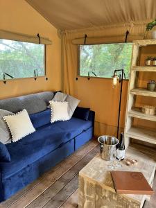 a living room with a blue couch and a table at Teal Safari Tent in Droitwich