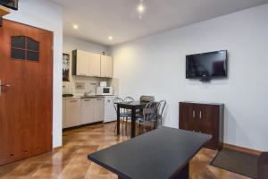 a kitchen with a table and a tv on a wall at Posejdon Wydmowa 16 3 in Lubiatowo +1 photo