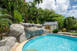 een zwembad in een tuin met rotsen en bomen bij Villa Olympus Ocean Vista Kata Beach in Kata Beach