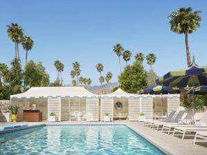 una piscina con tumbonas y sombrillas junto a un complejo turístico en Parker Palm Springs, en Palm Springs