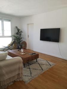 ein Wohnzimmer mit einem Tisch und einem TV an der Wand in der Unterkunft Appartement proche centre avec parking gratuit in Sèvres + 2 Fotos
