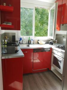eine Küche mit roten Schränken, einem Waschbecken und einem Fenster in der Unterkunft Appartement proche centre avec parking gratuit in Sèvres