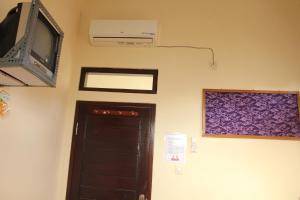 a room with a door and a tv and a wall at De Ibeel Guesthouse in Pangandaran