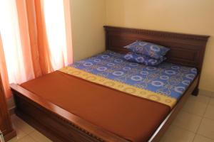 a bed with a wooden frame and a pillow on it at De Ibeel Guesthouse in Pangandaran