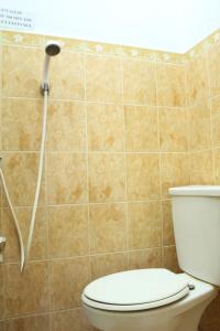 a bathroom with a toilet with a shower head at De Ibeel Guesthouse in Pangandaran