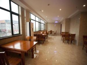a restaurant with wooden tables and chairs and windows at GreenTree Inn AnHui Maanshan Dangtu High Speed Railway East Station RT-Market Business Hotel in Ma'anshan