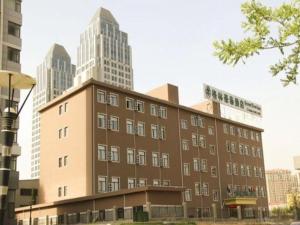 Ein braunes Gebäude mit hohen Gebäuden im Hintergrund in der Unterkunft GreenTree Inn ShanDong Yantai Yantai University Business Hotel in Yantai