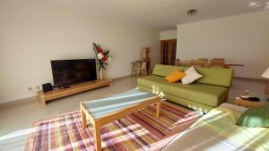 sala de estar con sofá verde y TV de pantalla plana en Vilamoura TOP MouraPraia, en Vilamoura
