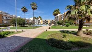 Un parque con palmeras y un edificio. en Vilamoura TOP MouraPraia, en Vilamoura