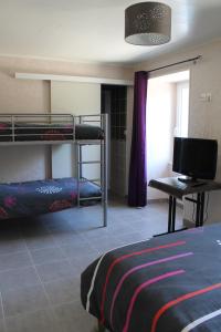 Pokój z 2 łóżkami piętrowymi i telewizorem w obiekcie Retour Aux Sources w mieście Meyras