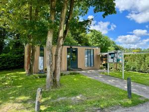 a small wooden house in a park with a tree at Villa Blue Sky in Heinkensand