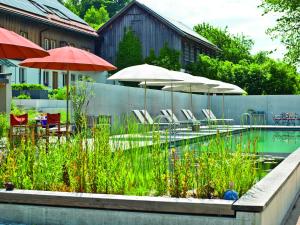 a swimming pool with umbrellas and chairs and tables at Biohotel Pausnhof in Sankt Oswald