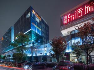 two cars parked in front of a building at night at Warmly Hotel Suzhou Shuanghuwan in Suzhou