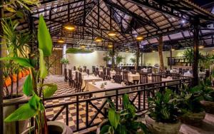 a restaurant with tables and chairs and plants at The Cyclo Siem Reap Hotel in Siem Reap