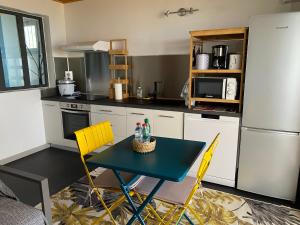 a kitchen with a blue table and yellow chairs at Location saisonnière A portée de vue in La Possession