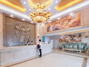 une femme debout dans une pièce avec des peintures sur le mur dans l'établissement Vienna Classic Hotel Guangdong Yangxi Moon Bay, à Dabang