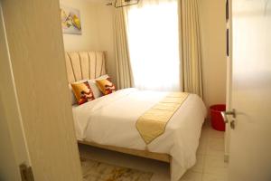 a bedroom with a white bed and a window at 1 bedroom Greenzone Apartment Thindigua, Kiambu Road in Nairobi +7 photos