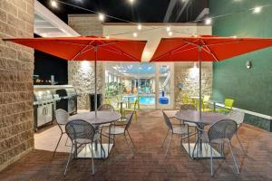 a patio with tables and chairs and red umbrellas at Home2 Suites by Hilton Green Bay in Green Bay