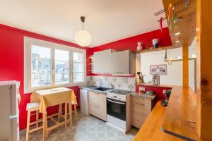 a kitchen with red walls and a table and a sink at L'Averia - Appartement spacieux en hypercentre in Blois