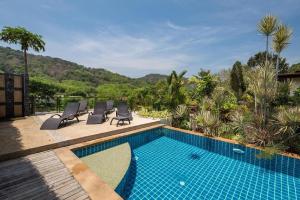 a swimming pool with lounge chairs next to a resort at Villa Oxavia in Rawai Beach