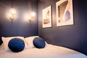 - une chambre avec 2 oreillers bleus sur un lit dans l'établissement OIQIA • Jadéa • Saphir, à Bressuire