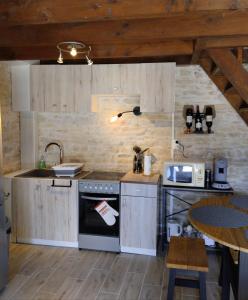 a kitchen with a stove and a sink and a table at Le petit nid du marais in Le Vanneau