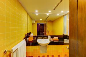 a yellow bathroom with a sink and a mirror at Hikka Tranz by Cinnamon in Hikkaduwa