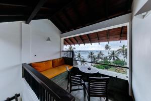 a balcony with a couch and a table and chairs at Hikka Tranz by Cinnamon in Hikkaduwa