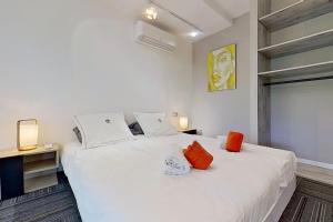 a bedroom with a white bed with orange pillows at VbyOnyx in Olmeto