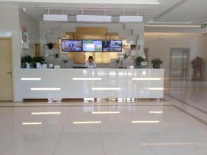 a woman standing behind a counter in a hospital lobby at GreenTree Inn Bozhou Qiaocheng District Bowu Industrial Park Business Hotel in Bozhou
