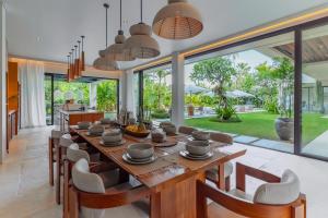 an open kitchen and dining room with a long wooden table and chairs at Villa Morada Canggu by Nakula in Dalung