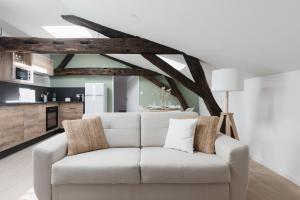 a white couch in a living room with wooden ceilings at OIQIA • Arthéa • Atelier in Périgueux