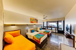 a hotel room with two beds and a flat screen tv at Hikka Tranz by Cinnamon in Hikkaduwa